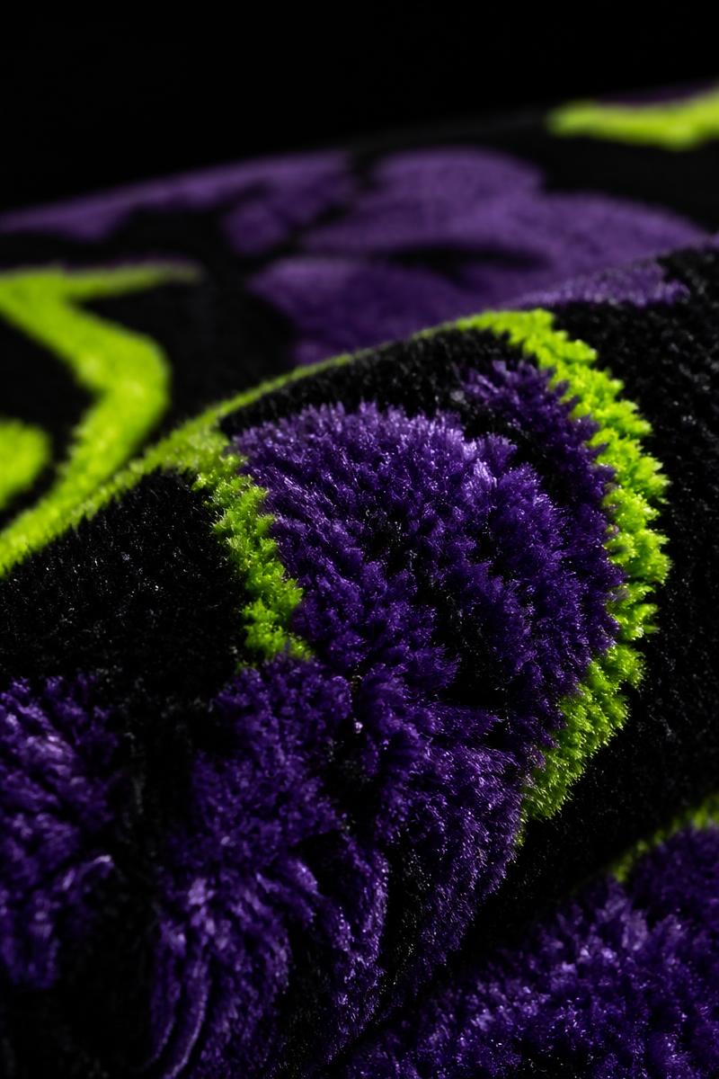Macro close-up of the rug's dense velvet pile in violet, black and green